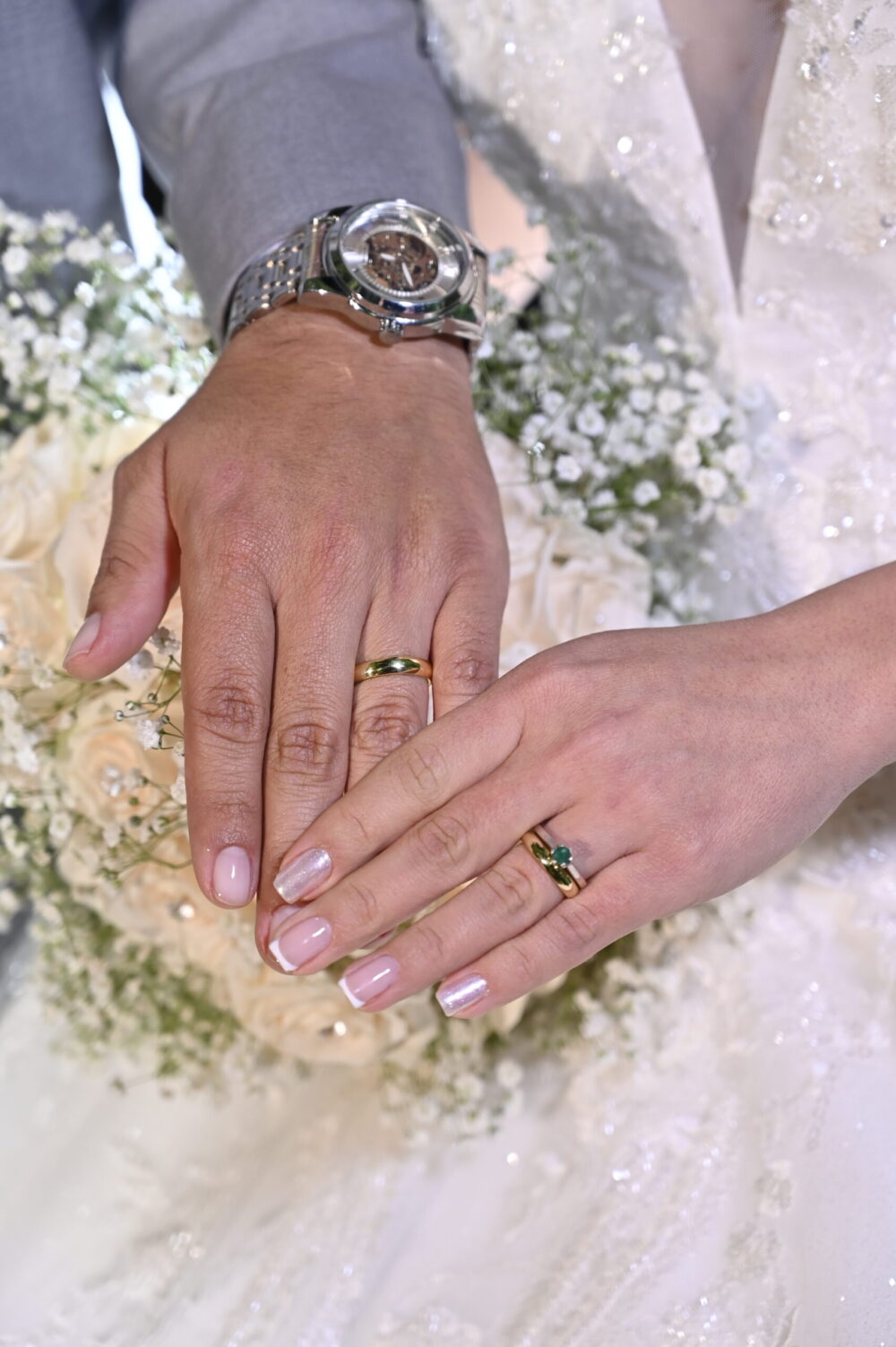 Pareja de novios con argollas de matrimonio en oro 18k y anillo de esmeralda